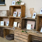 Palettes empilées les unes contre les autres, avec cadres photos pour faire le plan de table du mariage. Touches florales, coussins marrons, pampa