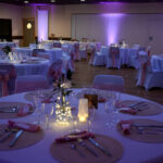 Salle de mariage avec tables rondes, décoration beige et rose et éclairage tamisé avec photophores