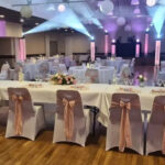 Vue d'ensemble de salle de mariage avec noeud de chaises roses, boules chinoises et éclairages,